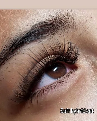 A close-up of a soft hybrid lash extension set on a shaped, brushed-up brow
