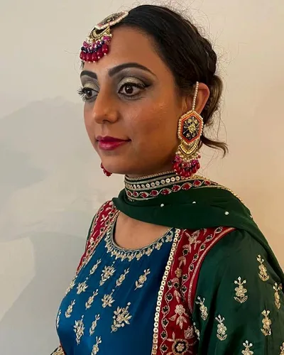 Festive makeup with a gold smoky eye and defined brows, worn with a maang tikka and jhumka earrings