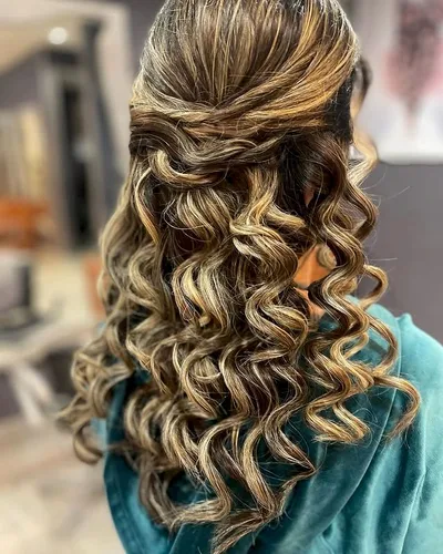 Half-up style with long spiral curls through caramel and honey highlights
