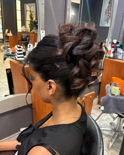 A dark curly updo pinned high, with loose tendrils left down around the face